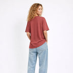 Person wearing a coral t-shirt and light blue jeans on a white background