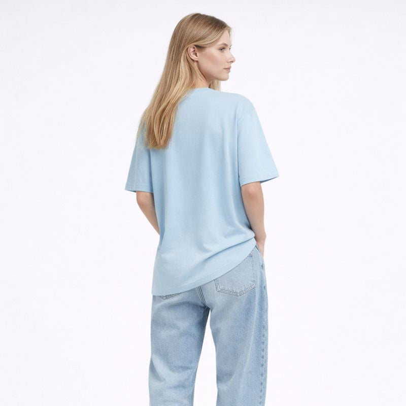 Woman wearing a light blue t-shirt and jeans on a white background