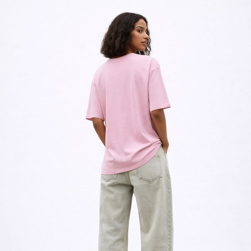 Person wearing a pink t-shirt and light gray pants on a white background