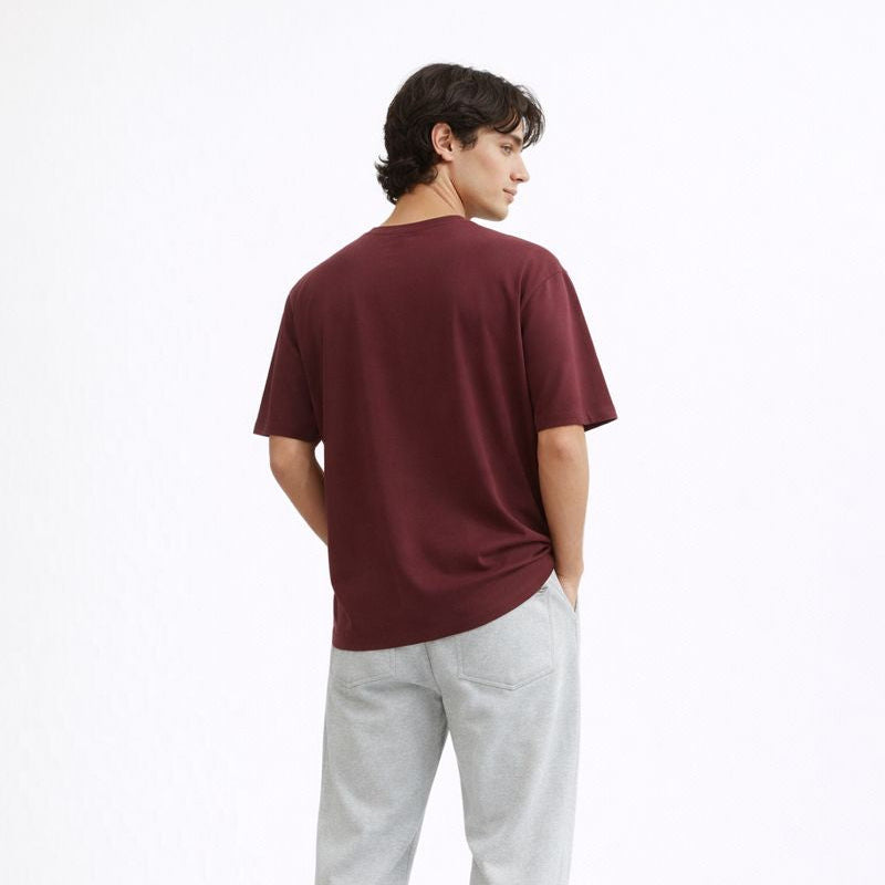 Person wearing a burgundy t-shirt and gray pants on a white background