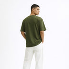 Man wearing a green t-shirt and white pants on a white background
