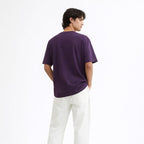 Person wearing a purple t-shirt and white pants on a white background