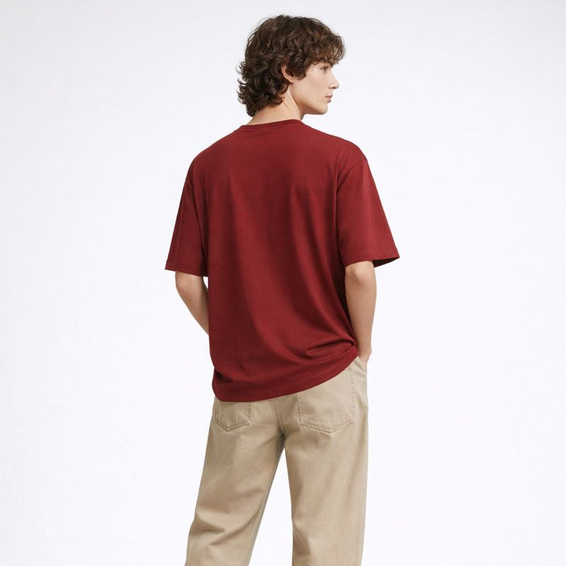 Person wearing a red shirt and beige pants on a white background