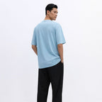 Man wearing a light blue t-shirt and black pants on a white background