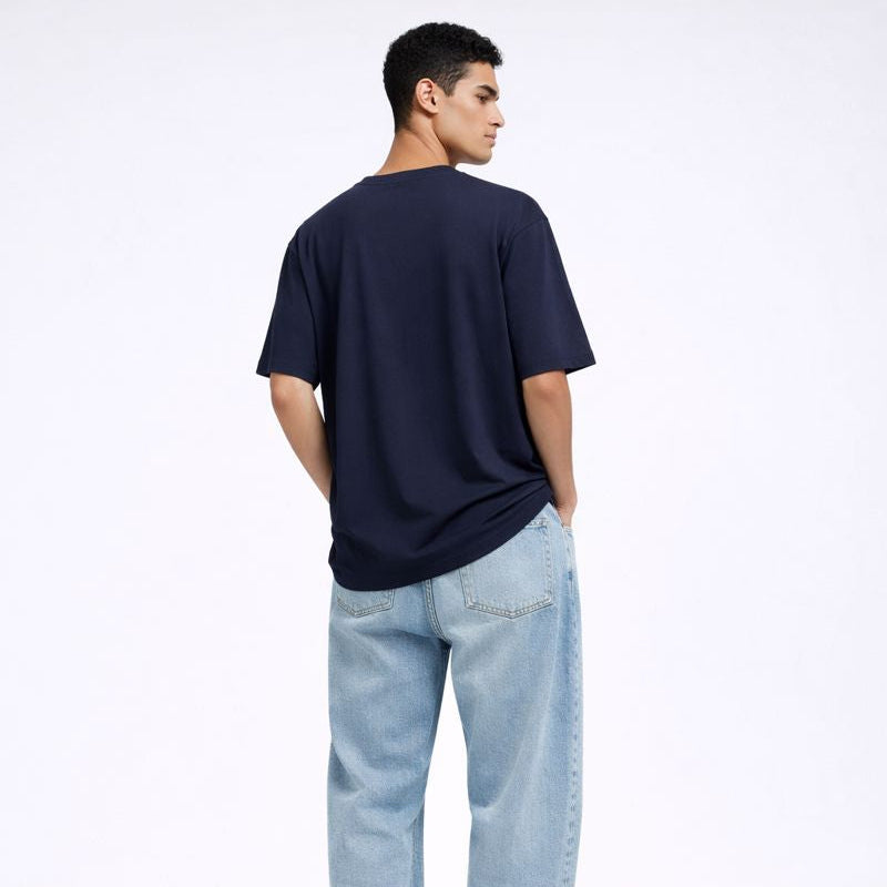 Person wearing a navy t-shirt and light blue jeans on a white background